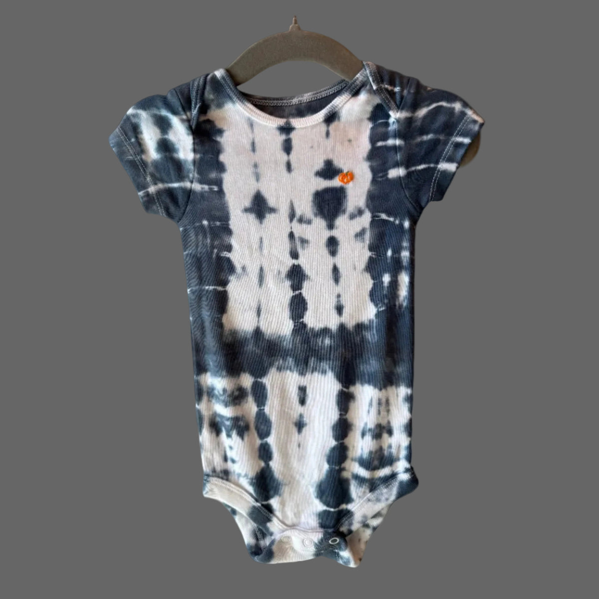 A short-sleeve cotton baby bodysuit with a midnight blue and white tie-dye pattern.