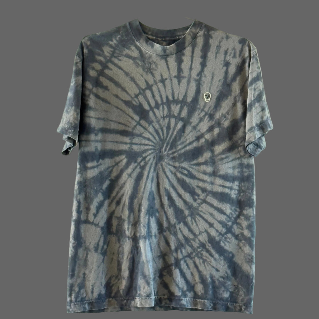 A short-sleeve cotton crewneck t-shirt featuring a black on faded black spiral tie-dye pattern with a hand embroidered skull on the upper right chest area.