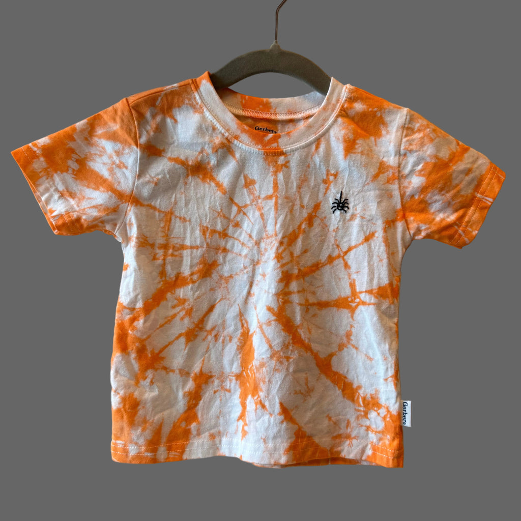A short-sleeve toddler' t-shirt with an orange and white spiral tie-dye pattern, featuring a small black hand embroidered spider.